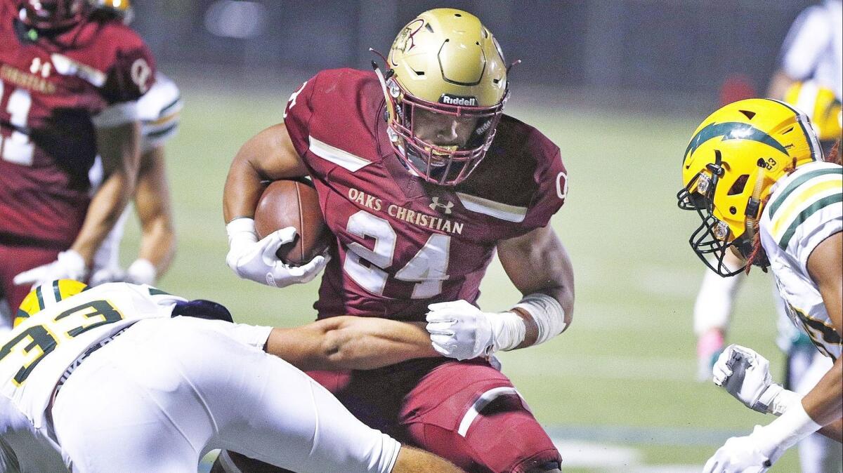 Oaks Christian High running back Zach Charbonnet carries the ball while Edison linebacker Luke Hoggard, left, tries to wrap him up in the second quarter on Friday.