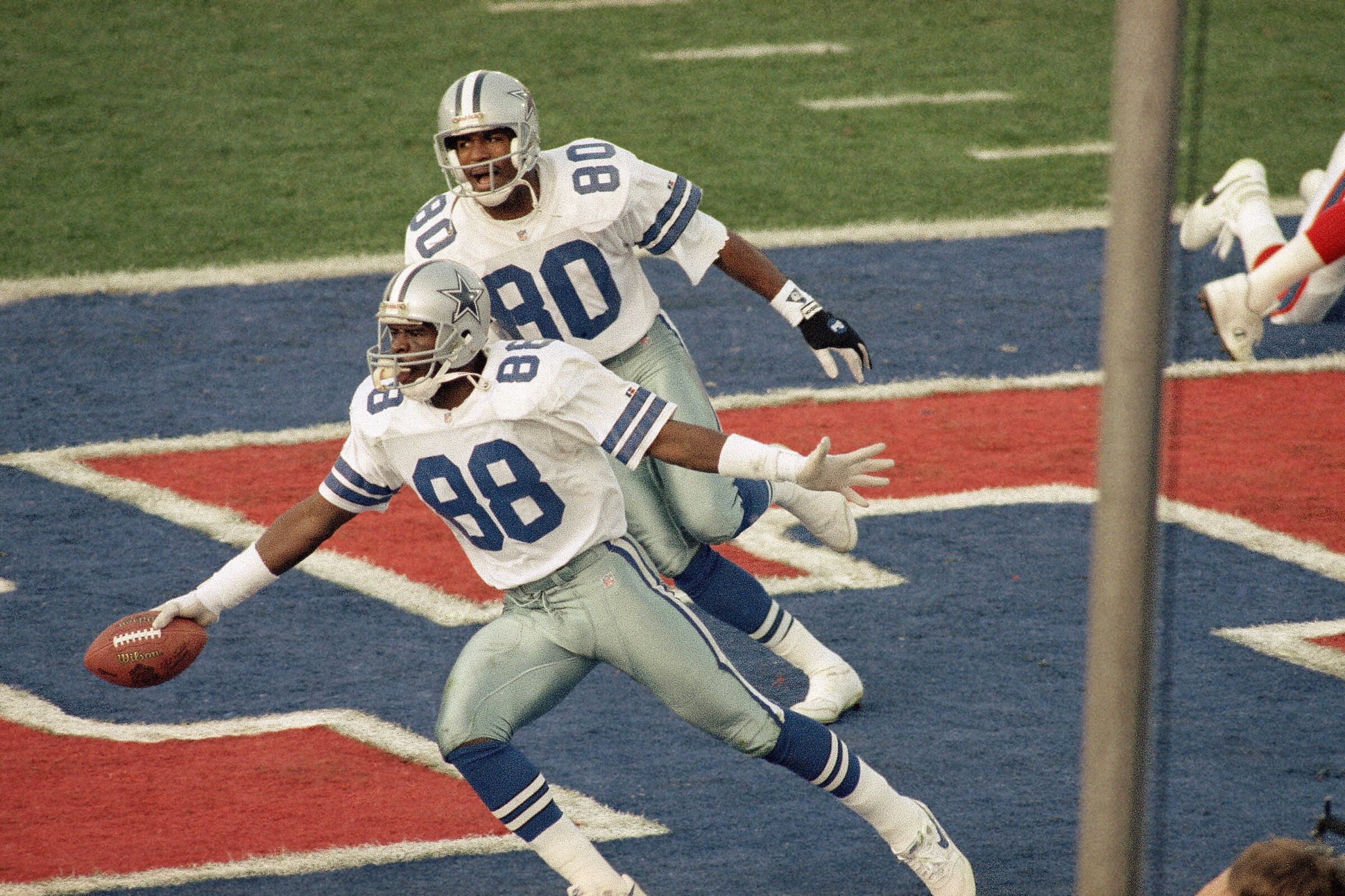 Dallas Cowboys Michael Irvin spreads his arms in celebration in the end zone as teammate Alvin Harper runs behind him.