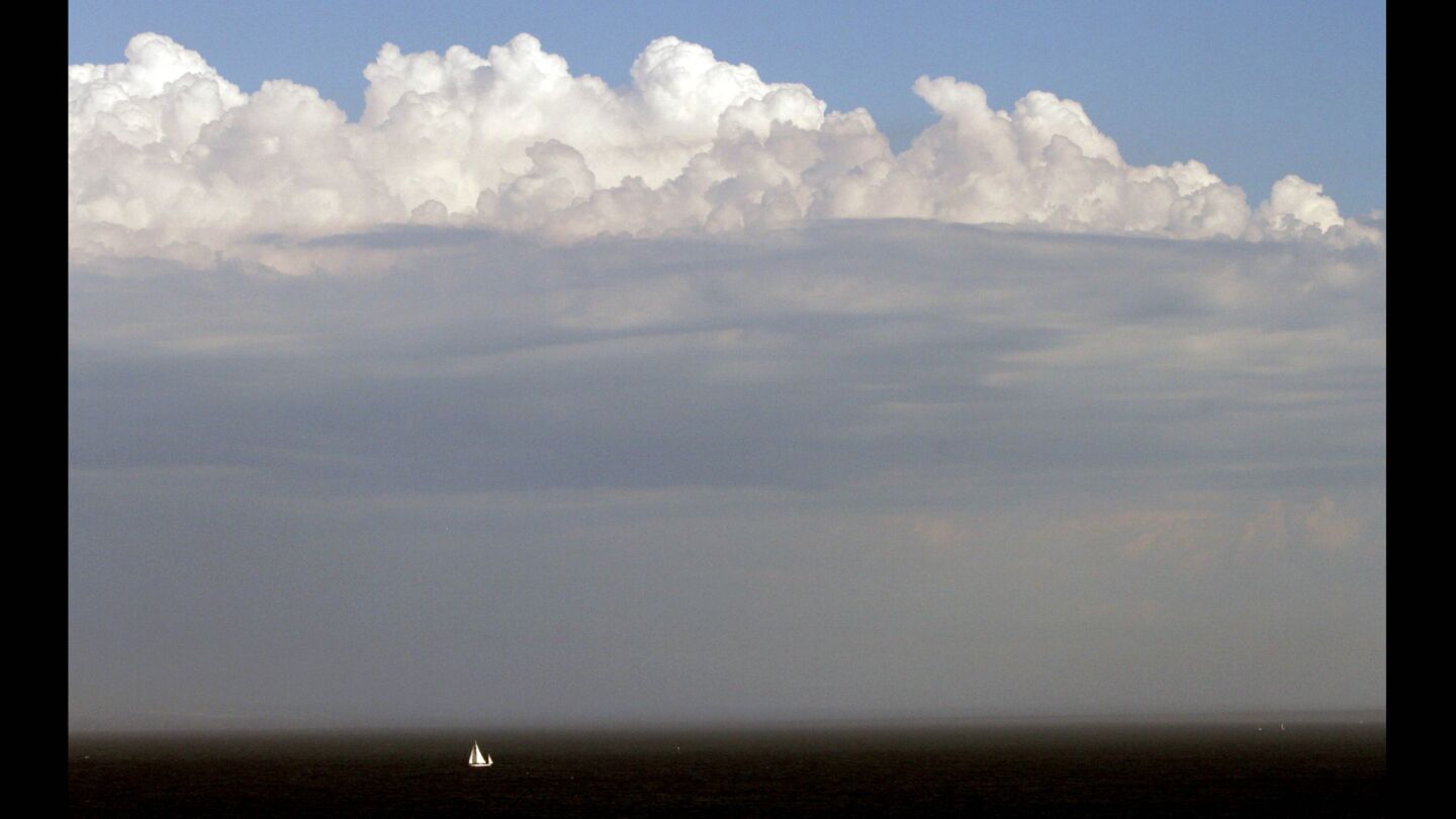 A huge thunderhead dwarfs a sailboat near the Angels Gate entrance to Los Angeles Harbor.