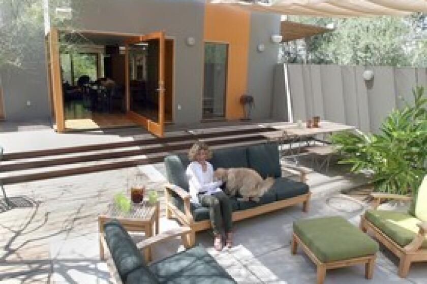 Sharon Bowman plays with her dog in her outdoor room in Los Angeles. When Bowman and husband Joe Fineman wanted to remodel their house, Culver City architect Lorcan OHerlihy suggested turning what had been the living room into an alfresco space. Ipe wood steps now lead from the house to a patio floor of concrete pavers and wood, all shaded by a retractable soft ceiling.