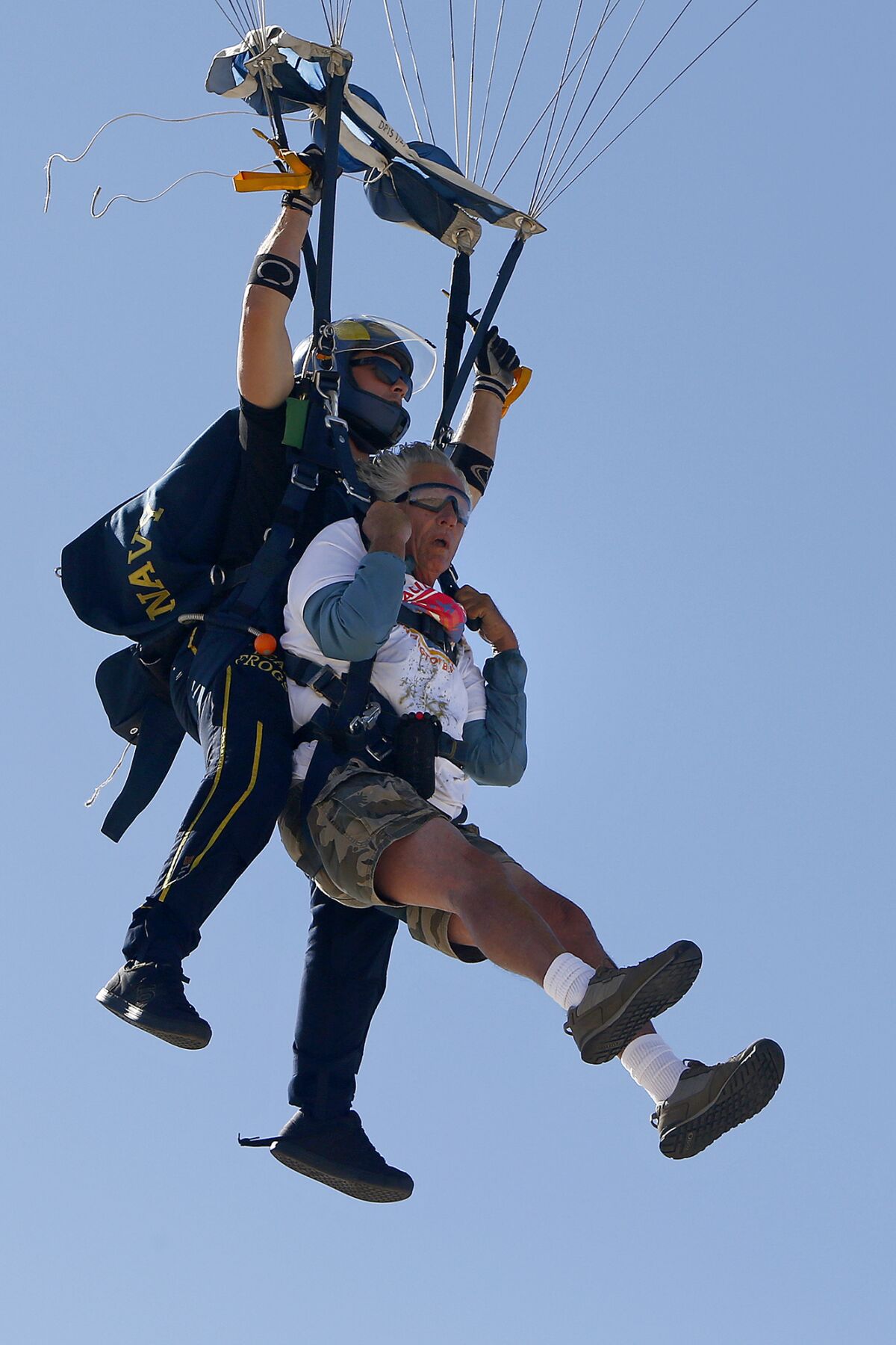 Don Ramsey, right, glides in for a landing after tandem jumping out of a plane with the U.S. Navy Leap Frogs on Thursday.