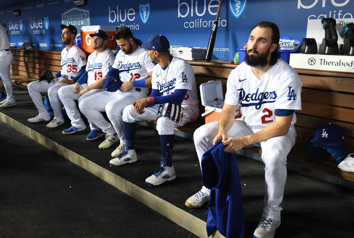 Dodgers pitcher Tony Gonsolin sits with other players in the dugout as he prepares to take the mound against the Rockies