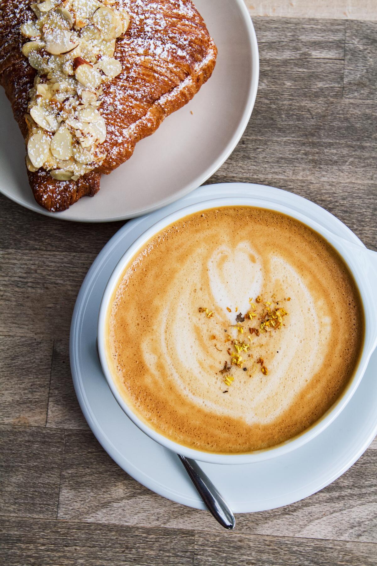 An overhead, vertical photo of a Gui Hua latte with an almond croissant