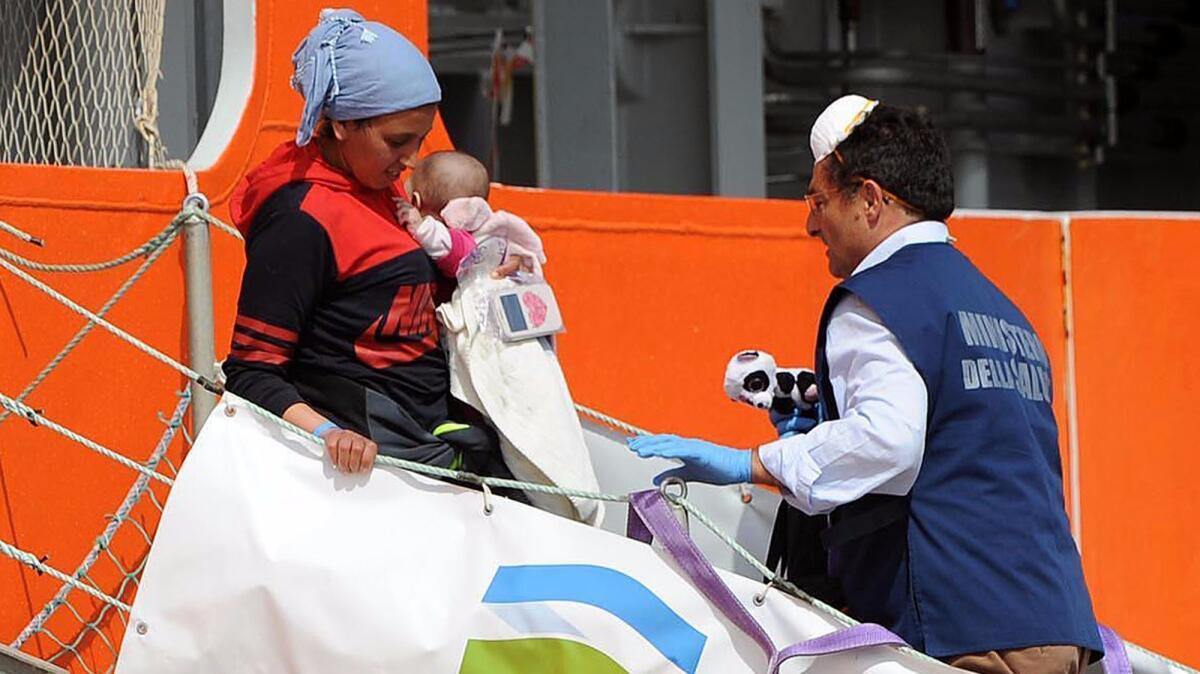 A woman carrying a baby disembarks May 9 from the Norwegian ship Siem Pilot, at the Salerno harbor, southern Italy.