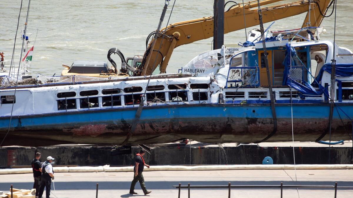 A crane on Tuesday places the wreckage of a sightseeing boat on a transporting barge at Margaret Bridge, the scene of the fatal boat accident in Budapest, Hungary.