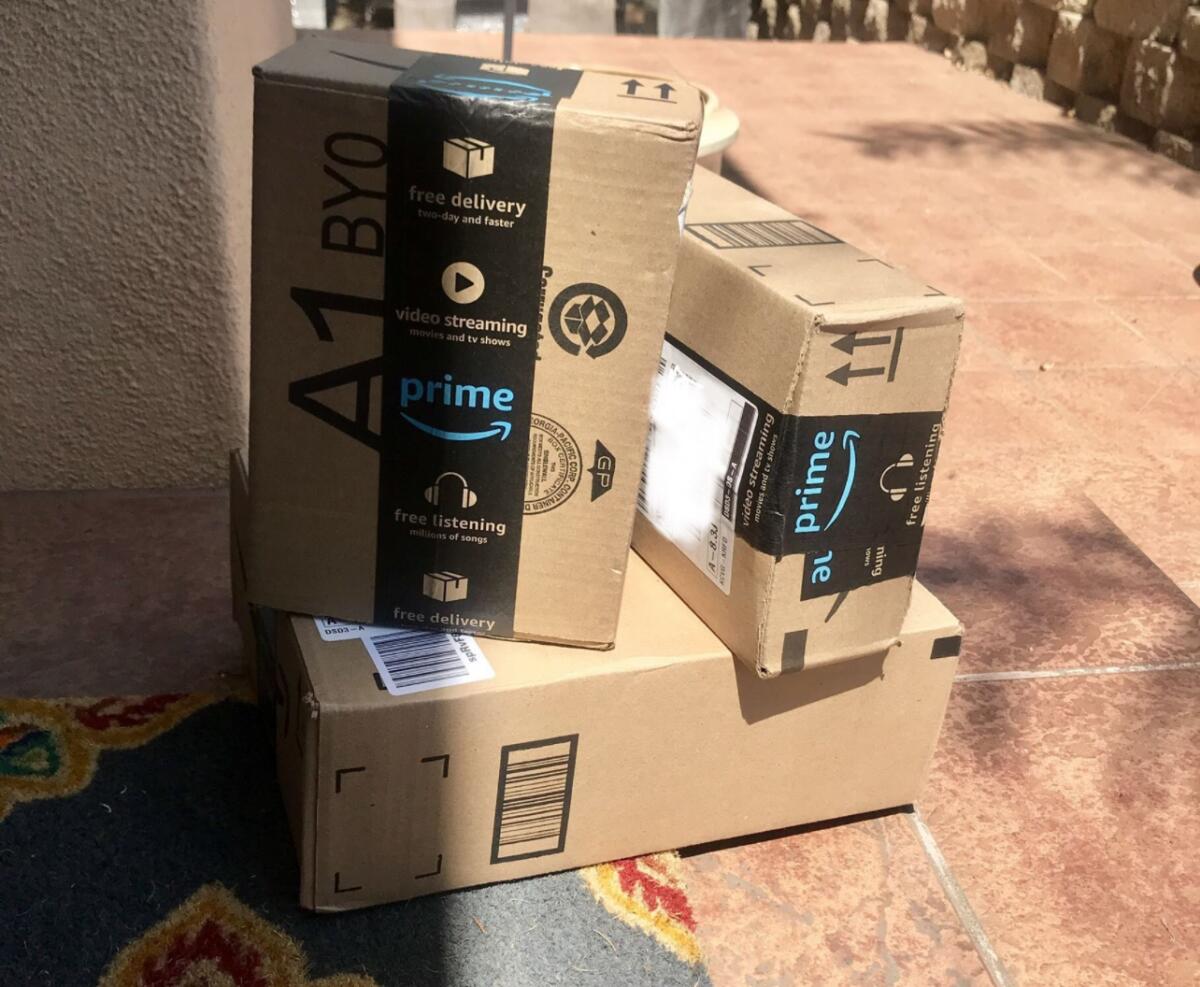 Two Amazon boxes rest on a third box at a doorstep.