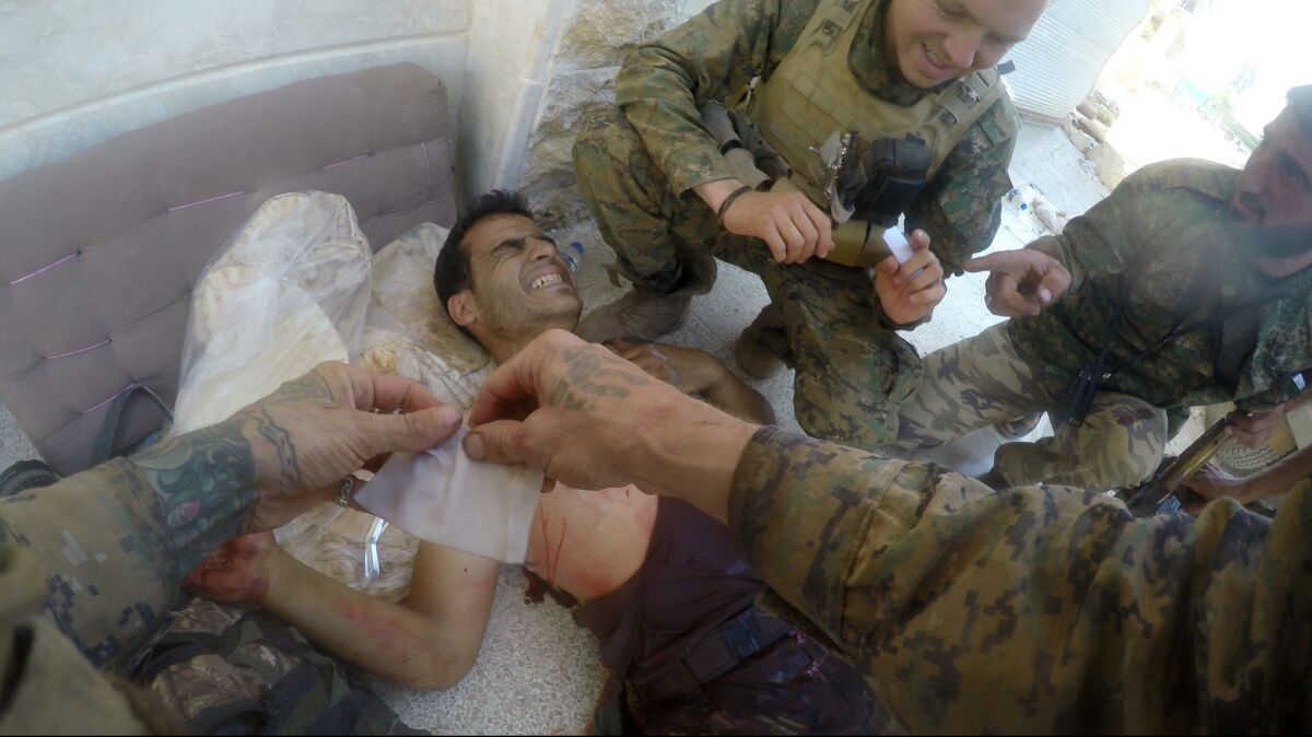 A photo taken by River Hagg shows Hagg (hands in photo) and Porter Goodman working on a casualty in Syria.