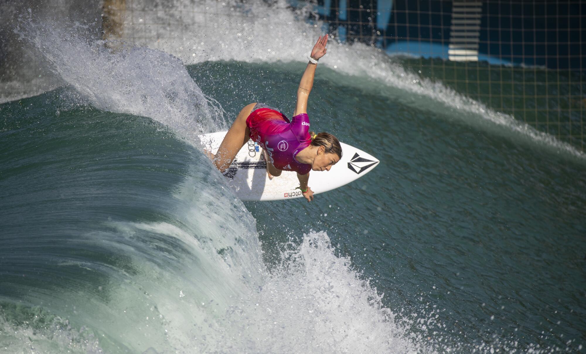 A surfer does a slashing turn off the top of a wave 