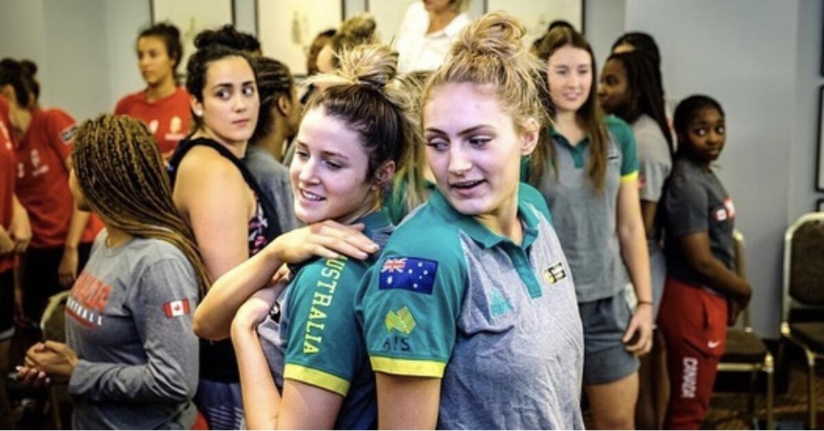 Two women stand back to back while other women are standing around behind them.