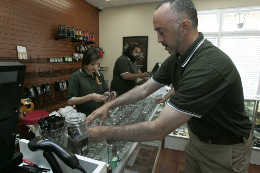 Zach Lazarus, right, COO of "A Green Alternative" medical marijuana dispensary in Otay Mesa, labeled bottles just before the opening of their office March 18..
