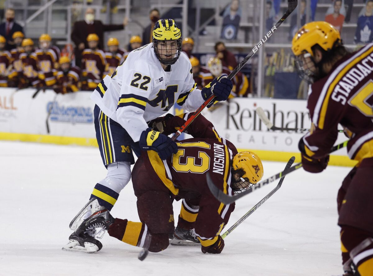 Michigan's Owen Power (22) and Minnesota's Cullen Munson (13) battle during an NCAA hockey game in December.