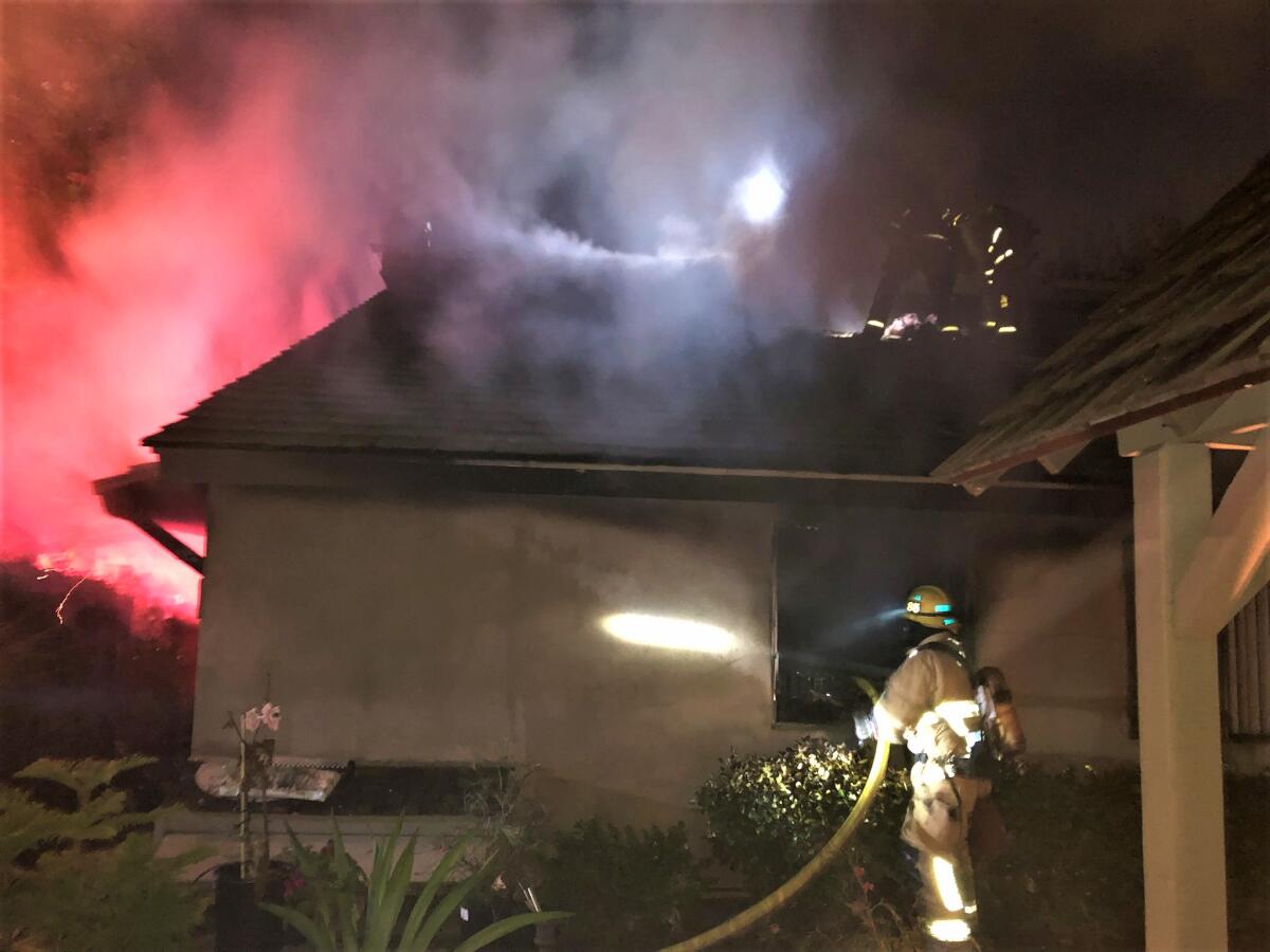 Fire personnel on Saturday ventilate a roof during a structure fire on the 100 block of Costa Mesa's 21st Street.