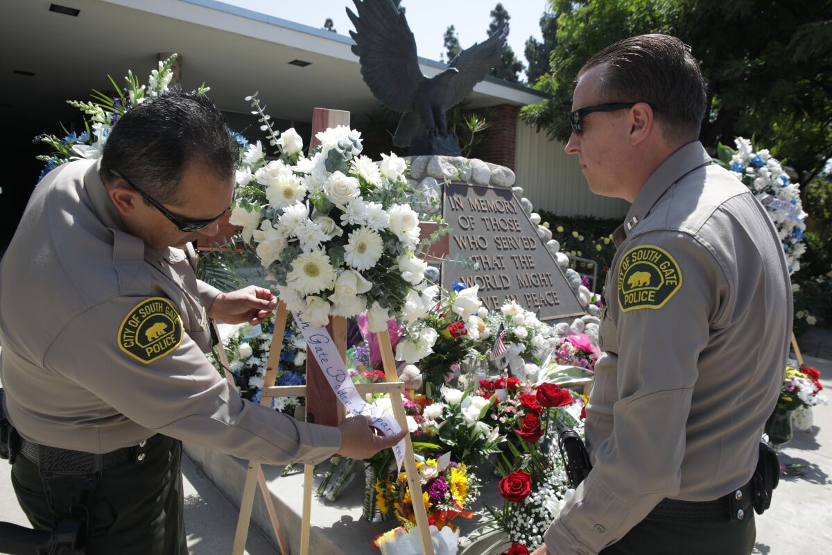 Police officers place flowers at a memorial 