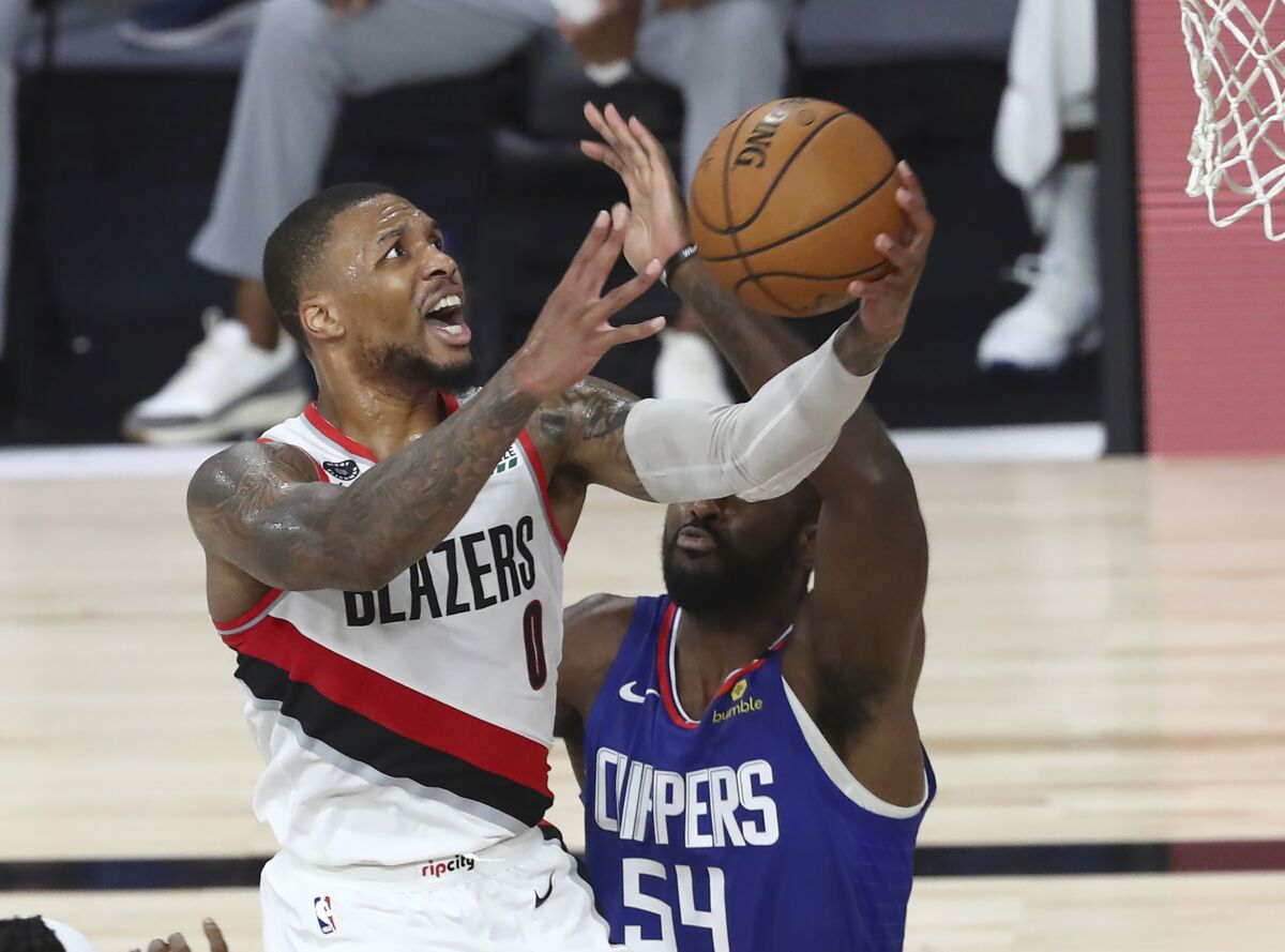 Trail Blazers guard Damian Lillard goes up for a shot against the Clippers' Patrick Patterson on Aug. 8, 2020.