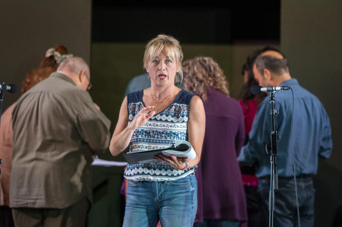 A woman stands at a microphone on the Fountain Theatre stage, back by her "Roe" cast mates in a circle behind her. 