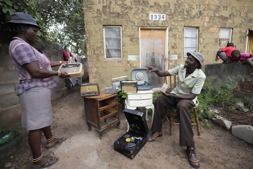 Ngwiza Khumbulani Moyo, right, a vintage collector, displays some of his old radio sets outside his home in Bulawayo, Wednesday, Feb. 15, 2023. In many Western countries, conventional radio has been overtaken by streaming, podcasts and on-demand content accessed via smartphones and computers. But in Zimbabwe and much of Africa, traditional radio sets and broadcasts are widely used, highlighting the digital divide between rich countries and those where populations struggle to have reliable internet. (AP Photo/Tsvangirayi Mukwazhi)