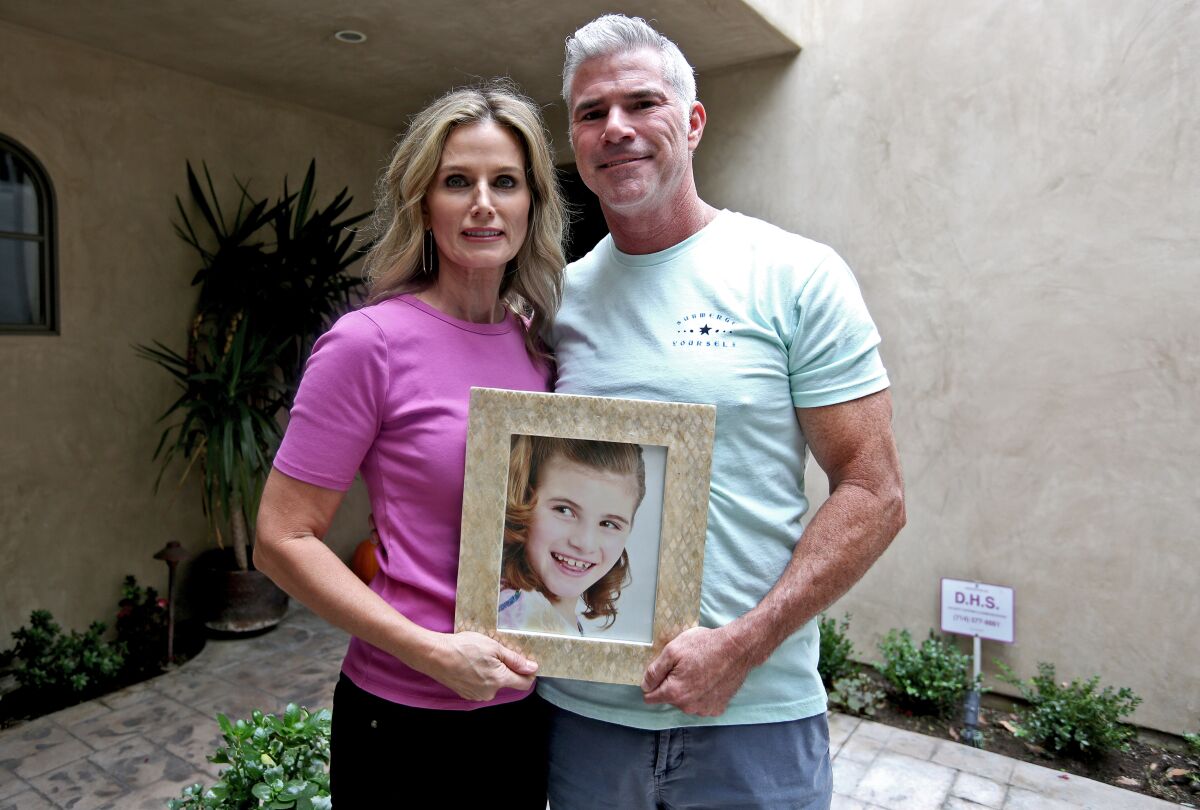 Alissa and Ron Murray, parents of Grace Murray, 17, hold a portrait of their daughter Ava.