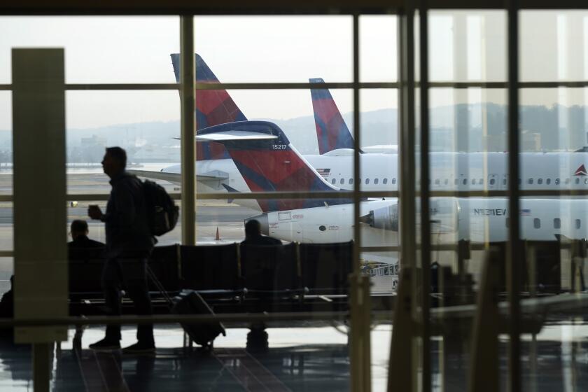 FILE - A person walks through the terminal as planes remain at gates at Ronald Reagan Washington National Airport in Arlington, Va., Wednesday, Jan. 11, 2023. The Federal Aviation Administration will investigate after a flight at Ronald Reagan Washington National Airport was instructed to cross a runway where another flight was starting its takeoff, the agency said, Thursday, April 18, 2024. (AP Photo/Patrick Semansky, File)