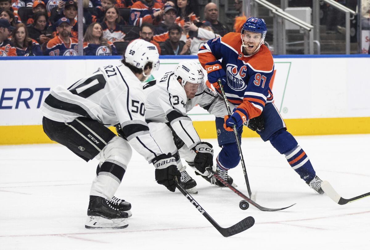 Kings' Sean Durzi and Arthur Kaliyev try to stop Edmonton Oilers' Connor McDavid.