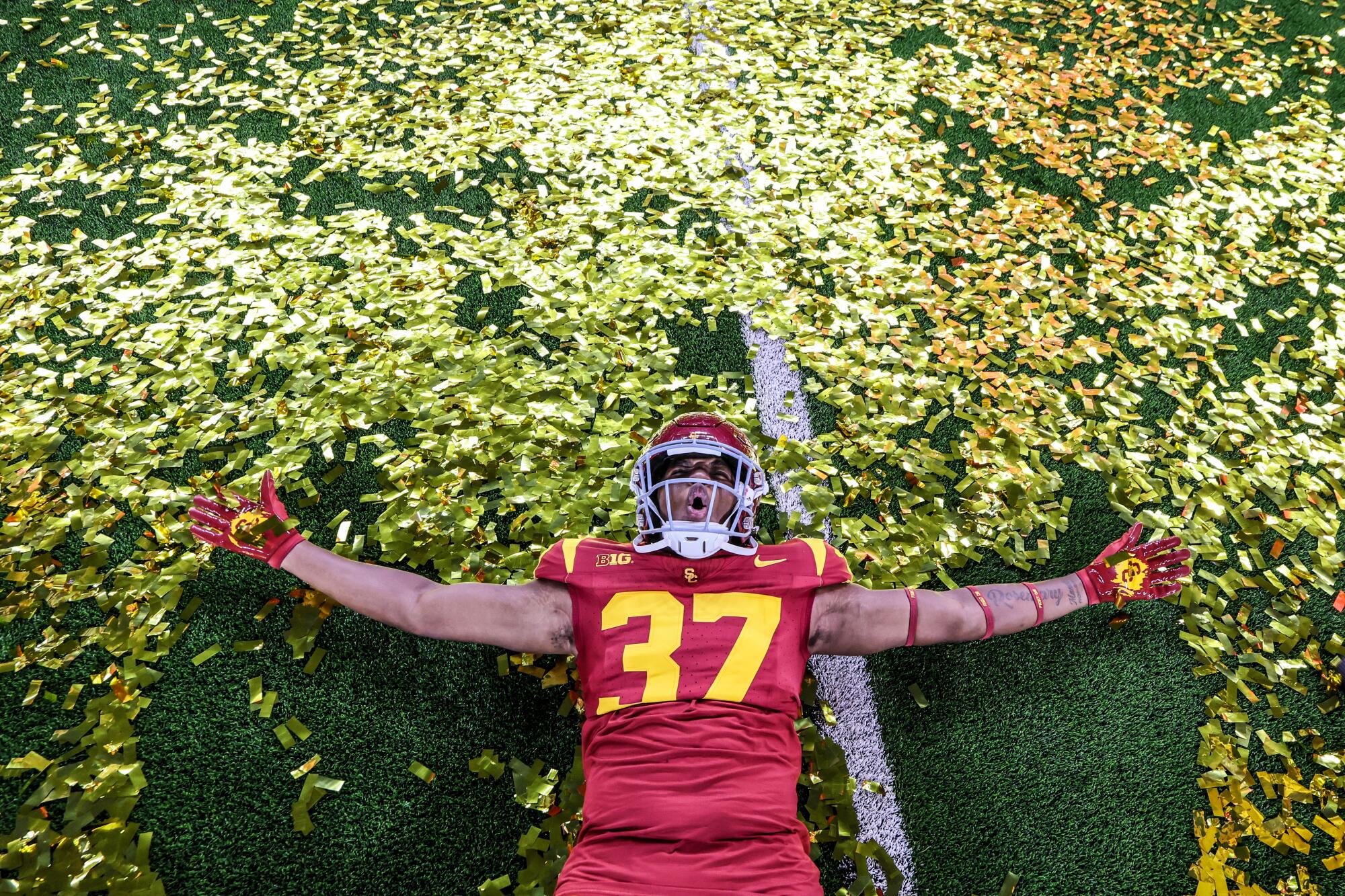 USC defensive end Lorenzo Cowan (37) makes a confetti angel on the field after the Trojans' win Sunday.