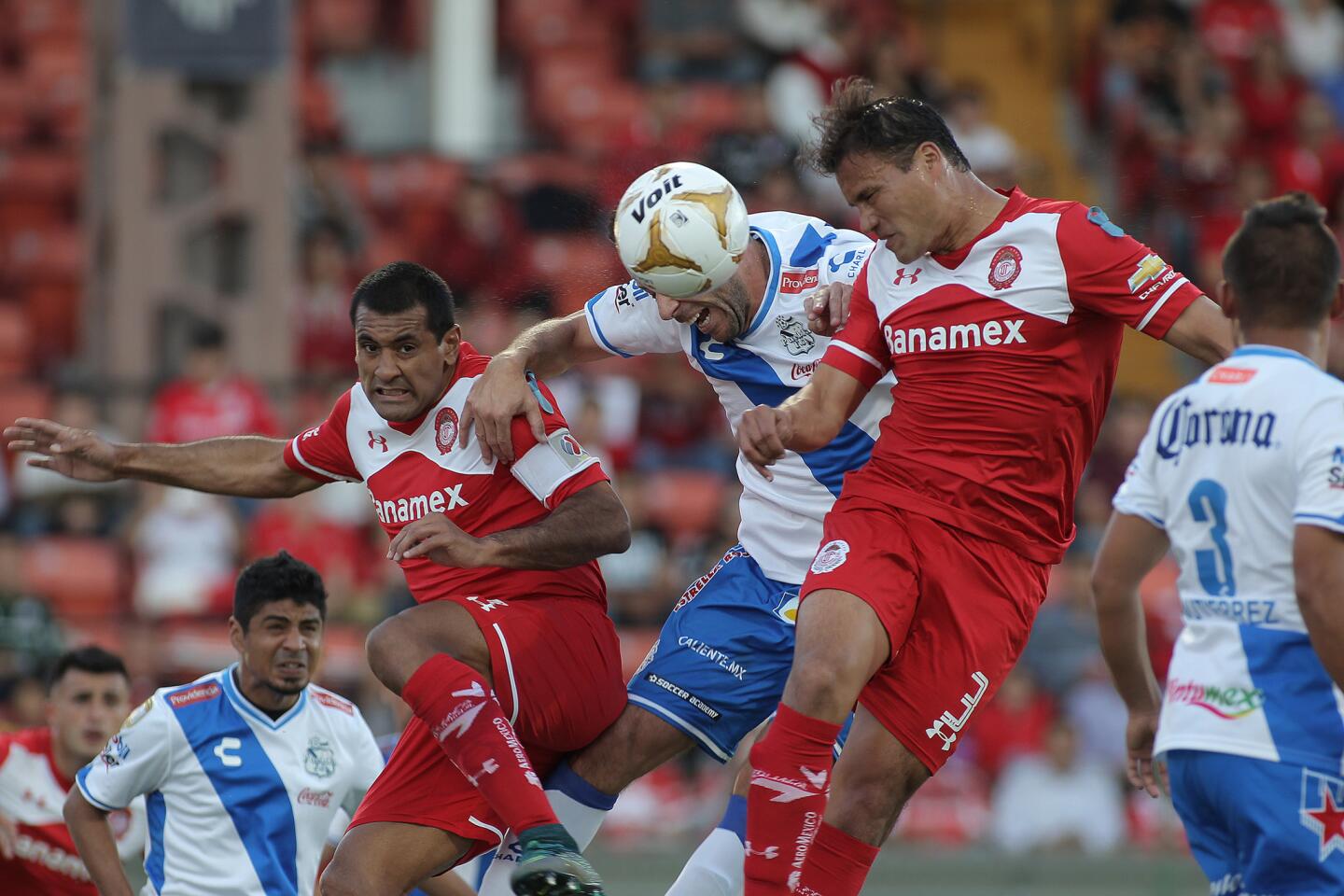 Aarón Galindo (i) y Paulo da Silva de Toluca disputan el balón contra Luis Gabriel Rey (c) de Puebla, durante el juego de vuelta de los cuartos de final del torneo mexicano de fútbol celebrado en el estadio Nemesio Diez en la Ciudad de Toluca (México).