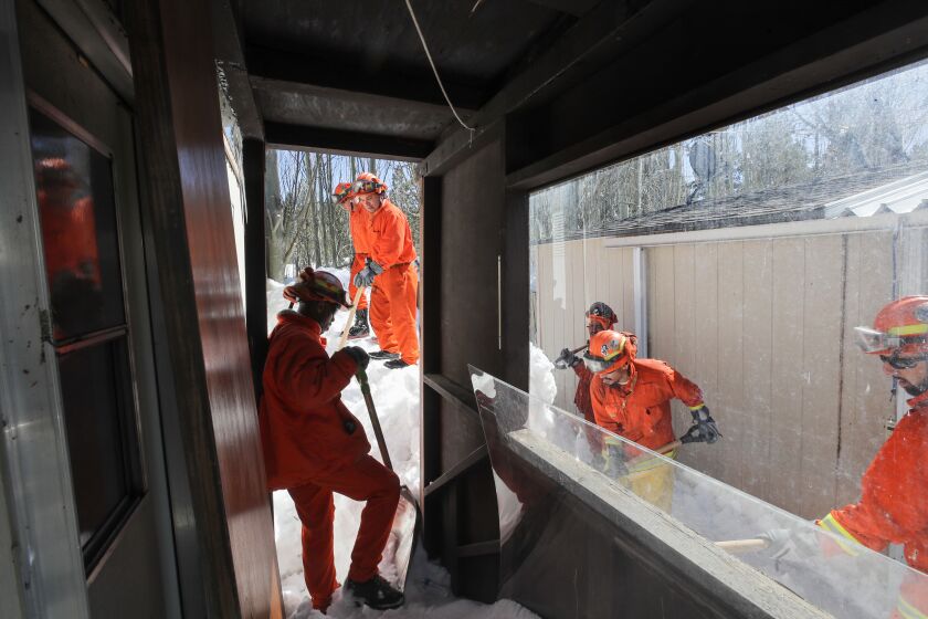 BIG BEAR LAKE, CA - MARCH 03: Cal Fire Fenner Canyon fire crew inmates dig snow from around a residence at a Big Bear Lake trailer park on Friday, March 3, 2023 in Big Bear Lake, CA. (Brian van der Brug / Los Angeles Times)