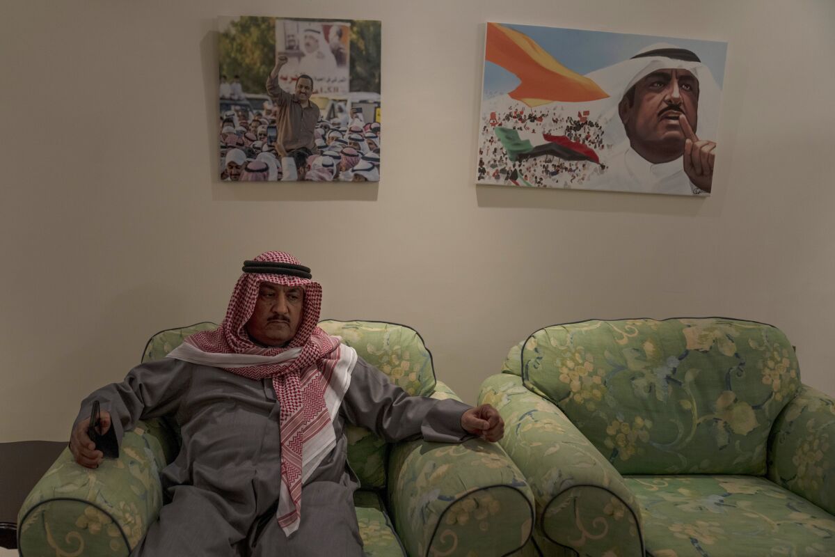 Former opposition leader Musallam al-Barrak sits beneath a photo and painting of him during rallies, at his home in Kuwait City, Feb. 9, 2022. A decade ago, and against all odds, the surge of uprisings known as the Arab Spring reached emir-ruled Kuwait as dissidents stormed parliament and demanded the downfall of the prime minister. Al-Barrak and other dissidents, driven into exile have returned home to a country they say has only deteriorated in their absence. (AP Photo/Maya Alleruzzo)