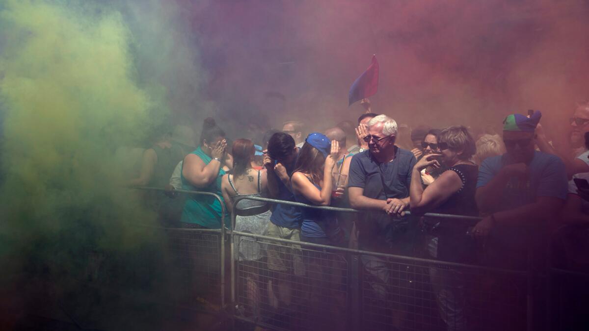 Spectators cover their faces after colorful smoke grenades were set off by members of the Black Lives Matters movement at the annual Pride Parade in Toronto on July 3.