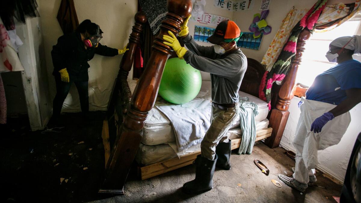 From left, Lupe Bernal, Saul Galvan and Nikki Fields work quickly to dismantle the bedroom furniture that was damaged by floodwater in Houston.