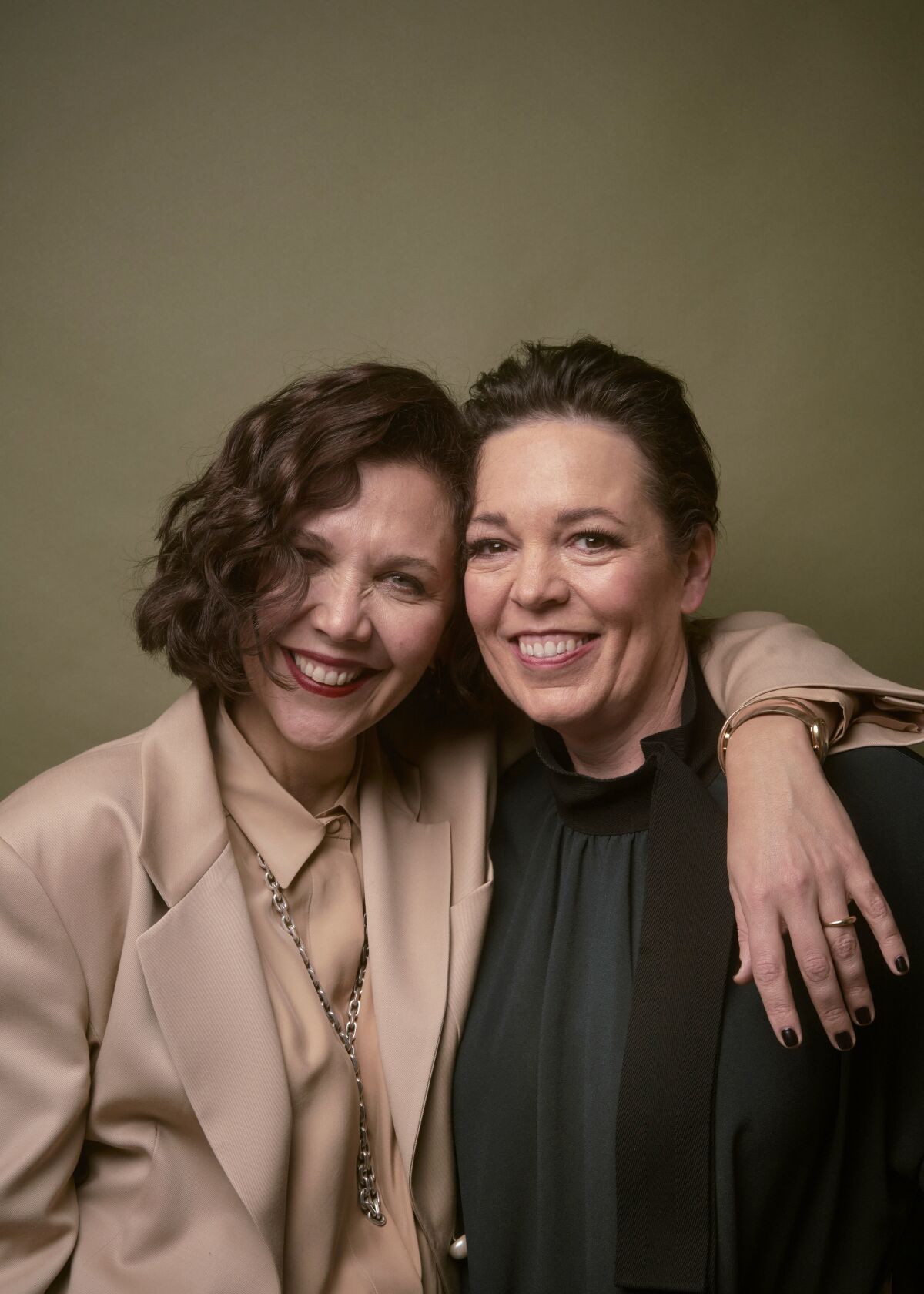 Two women put their heads together and smile for a portrait.