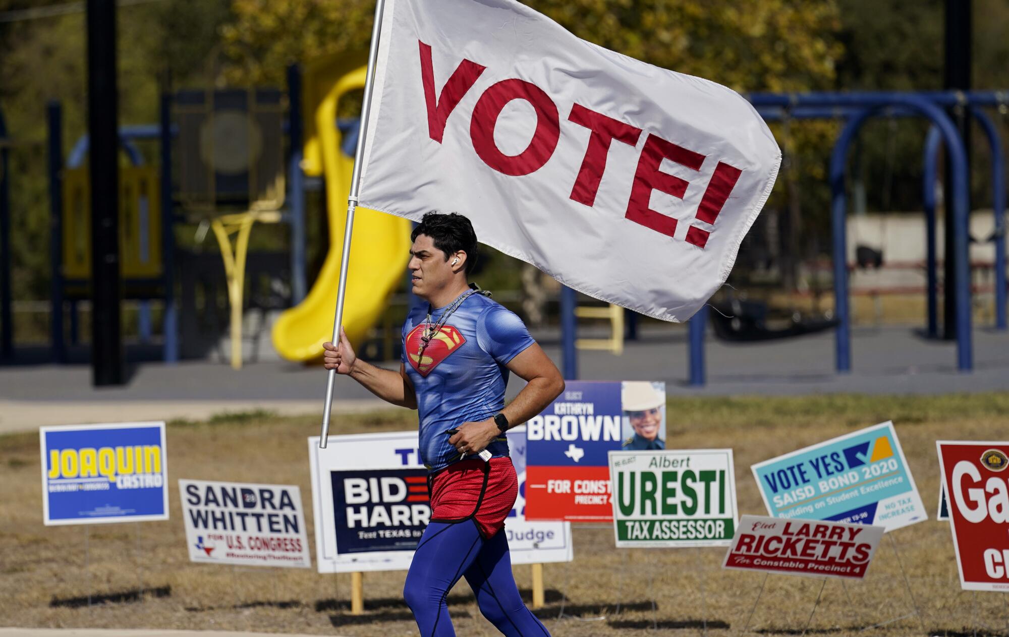 Al pasar por una casilla electoral en San Antonio, un corredor lleva una bandera para animar a la gente a votar.
