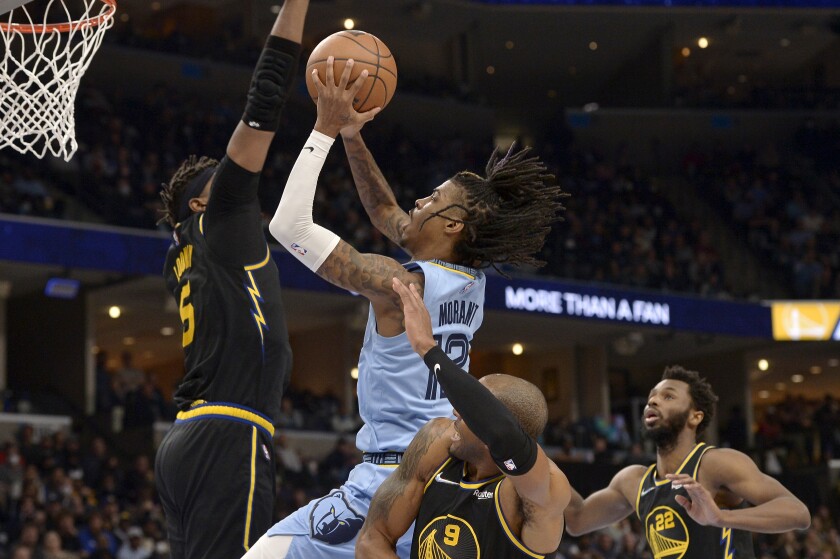 Memphis Grizzlies guard Ja Morant (12) shoots against Golden State Warriors center Kevon Looney (5), and forwards Andre Iguodala (9) and Andrew Wiggins (22) in the second half of an NBA basketball game Tuesday, Jan. 11, 2022, in Memphis, Tenn. (AP Photo/Brandon Dill)