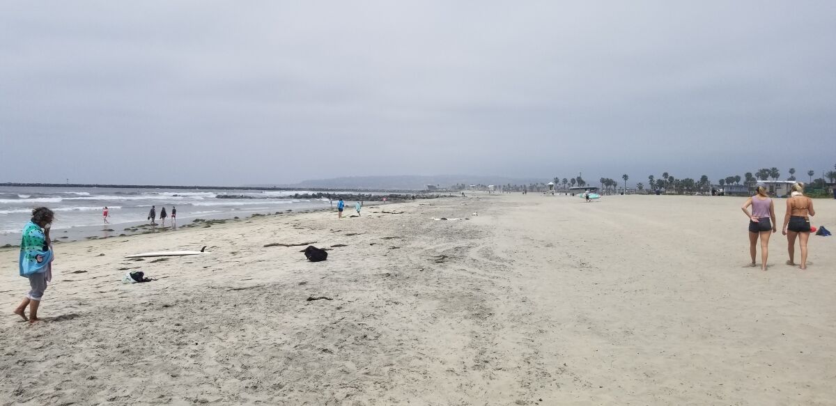 Visitors to the coastline in Ocean Beach keep their distance from one another after San Diego beaches reopened for limited use after being closed for roughly a month to prevent crowds amid the coronavirus outbreak.