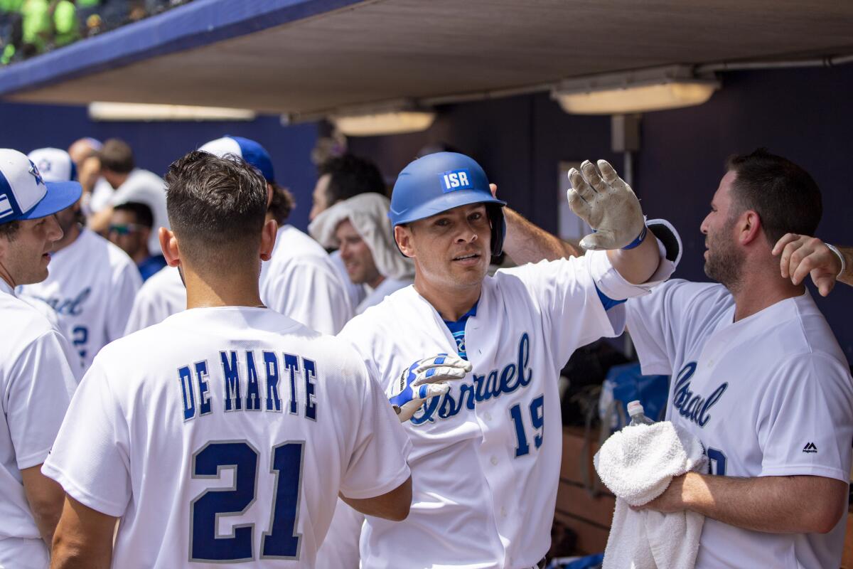 Israel infielder Danny Valencia, center, celebrates with teammates in the dugout during an exhibition game.
