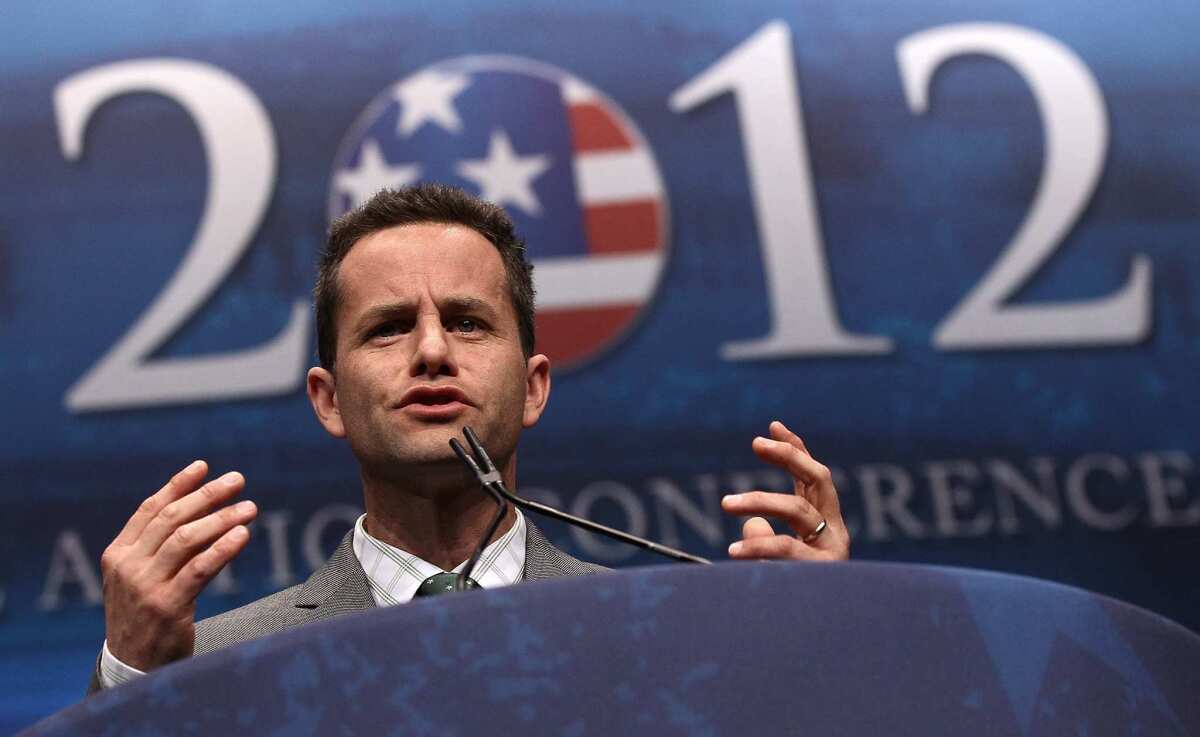 Kirk Cameron speaks at a lectern in front of a sign saying "2012."