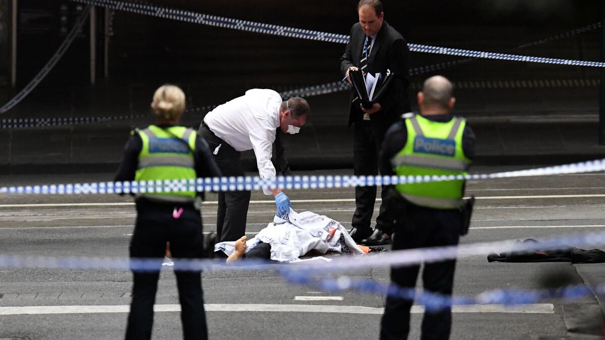 A police officer inspects a body at the crime scene after a stabbing attack in Melbourne, Australia, on Nov. 9.