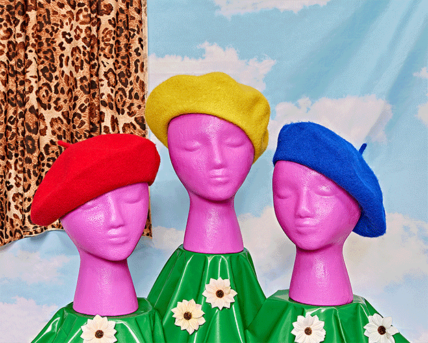 Gif of berets spinning on three fake pink heads.