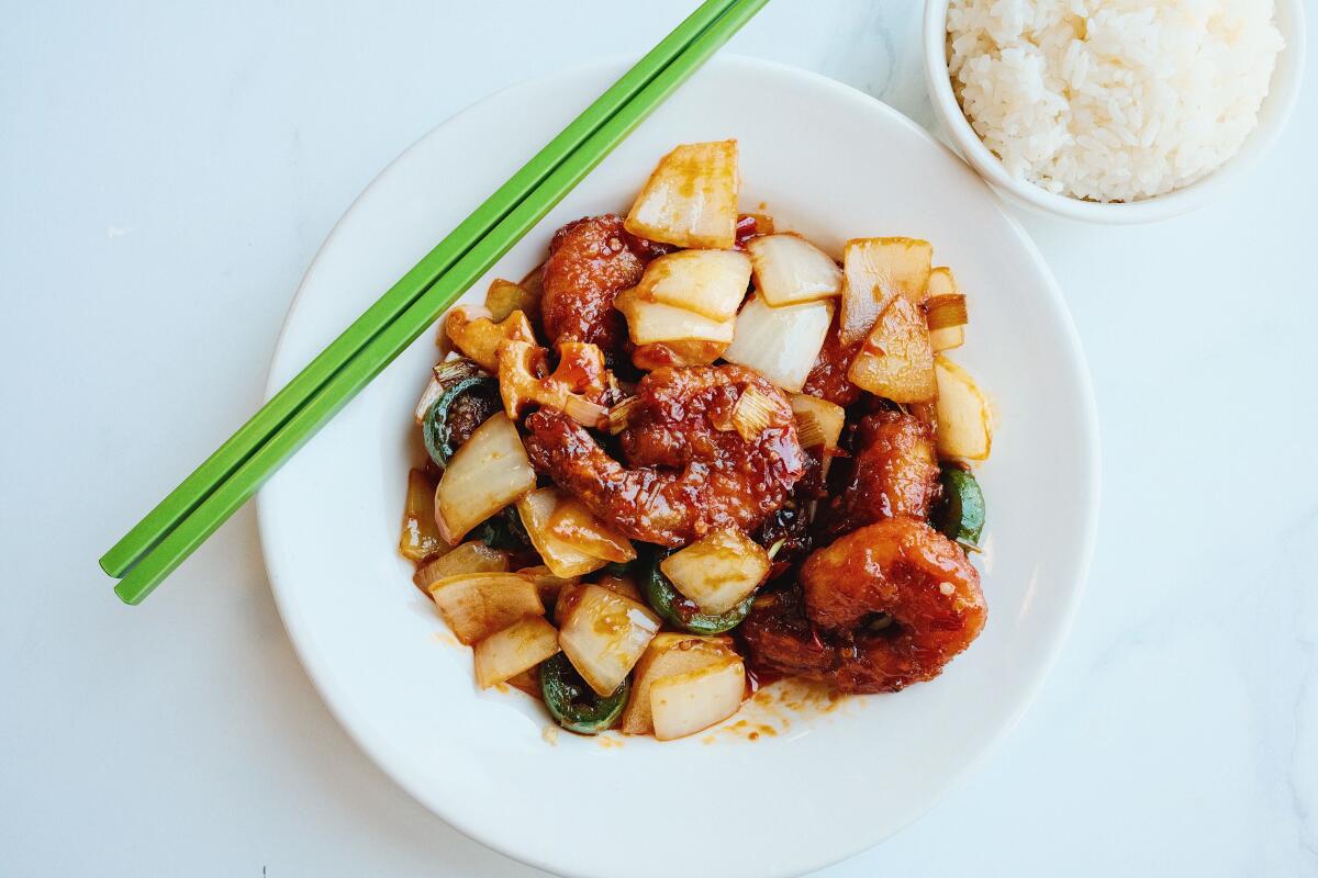 Crispy shrimp and onions in a white bowl at Highland Park restaurant Mala Class, white rice and green chopsticks at side