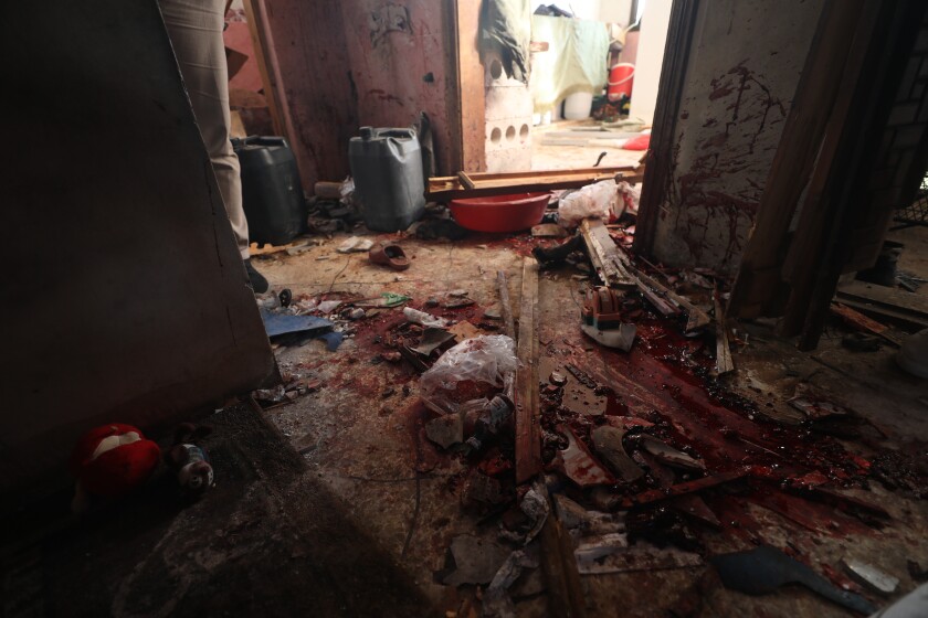 The bloodstained floor of a house with debris strewn about 