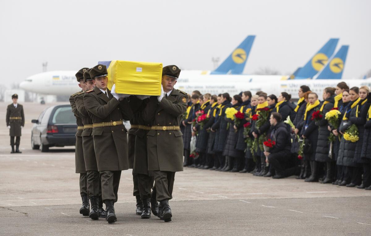 An honor guard carries a coffin of the one of the 11 Ukrainians who were among victims when their plane was shot down by an Iranian missile.