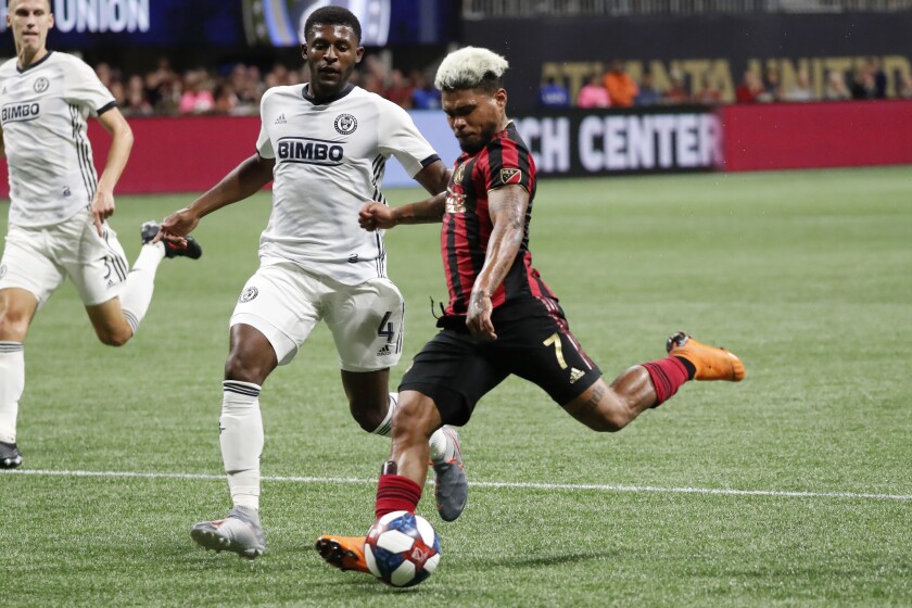 FILE - In this Oct. 24, 2019, file photo, Atlanta United forward Josef Martinez (7) scores a goal as Philadelphia Union defender Mark McKenzie (4) defends during the second half of an MLS soccer Eastern Conference semifinal in Atlanta. One of the most dynamic strikers in Major League Soccer history, and the face of Atlanta United's stunning rise to the top of the league, Martinez missed nearly all of last season recovering from a serious knee injury. (AP Photo/John Bazemore, File)