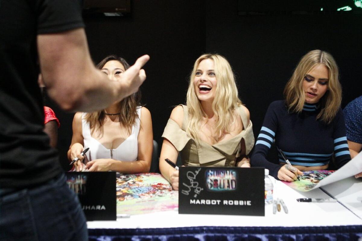 Actor Margot Robbie, center, laughs as she signs autographs during a "Suicide Squad" event at last week's Comic-Con.