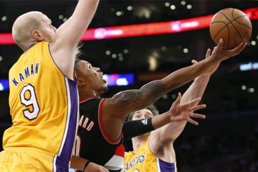 Portland guard Damian Lillard shoots between Lakers' Chris Kaman and Pau Gasol.
