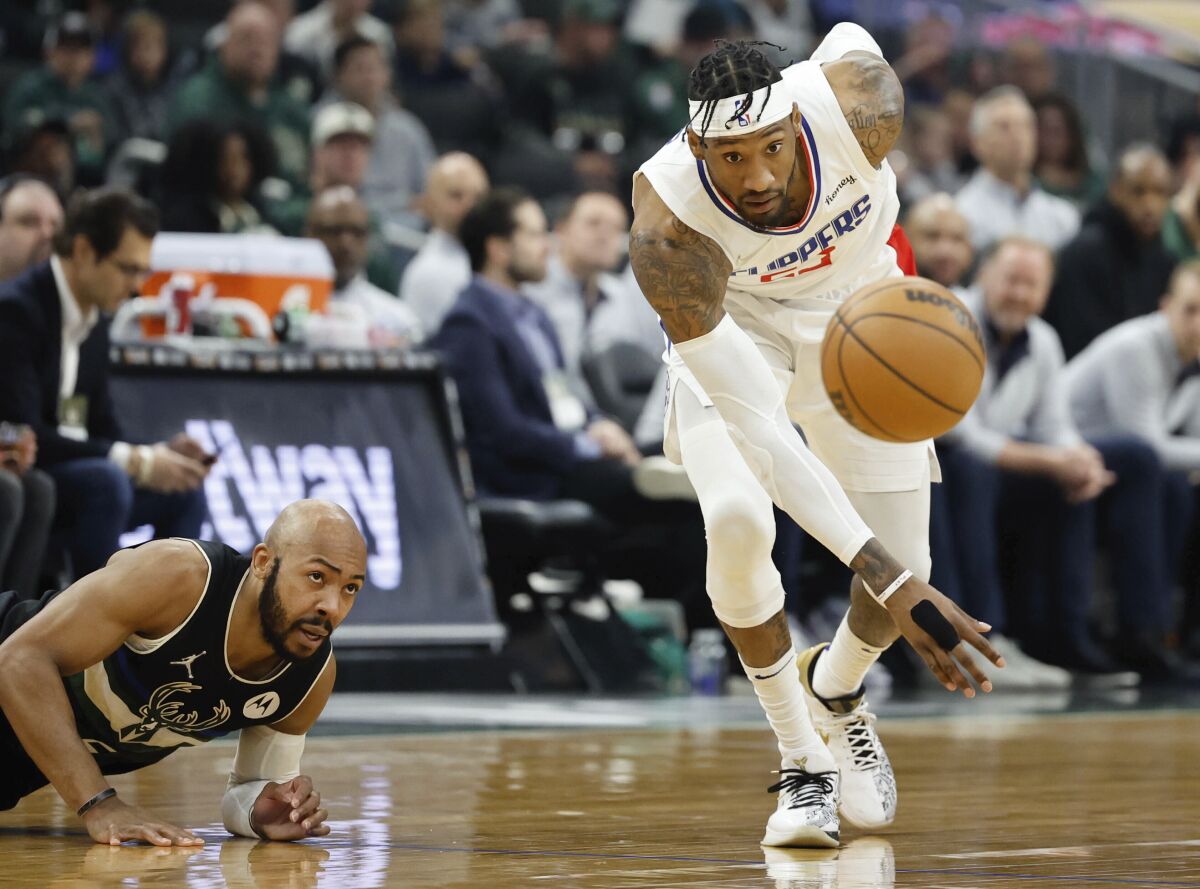 Clippers forward Robert Covington chases down a loose ball as Bucks guard Jevon Carter falls to the court.