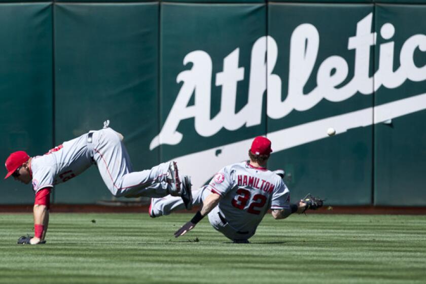 Angels outfielders Mike Trout and Josh Hamilton get tangled after failing to chase down a fly ball by Oakland's Stephen Vogt in the sixth inning Sunday afternoon.