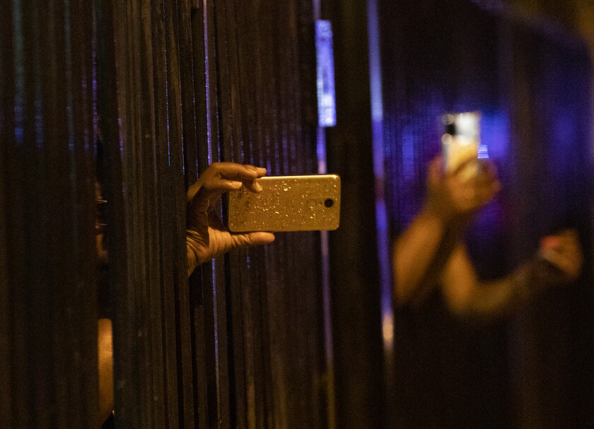 Residents film a few people being taken into custody Tuesday in Los Angeles.