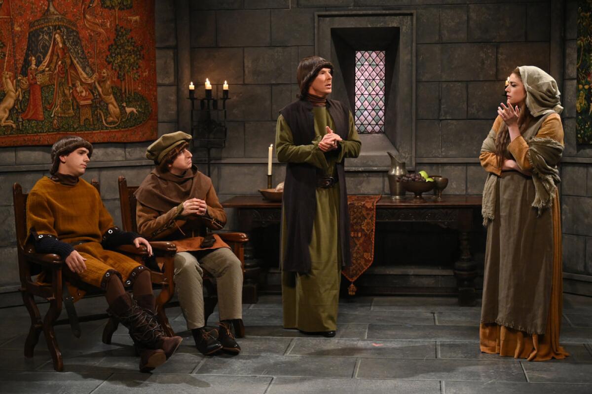 Four people in old-fashioned clothing standing inside a stone castle