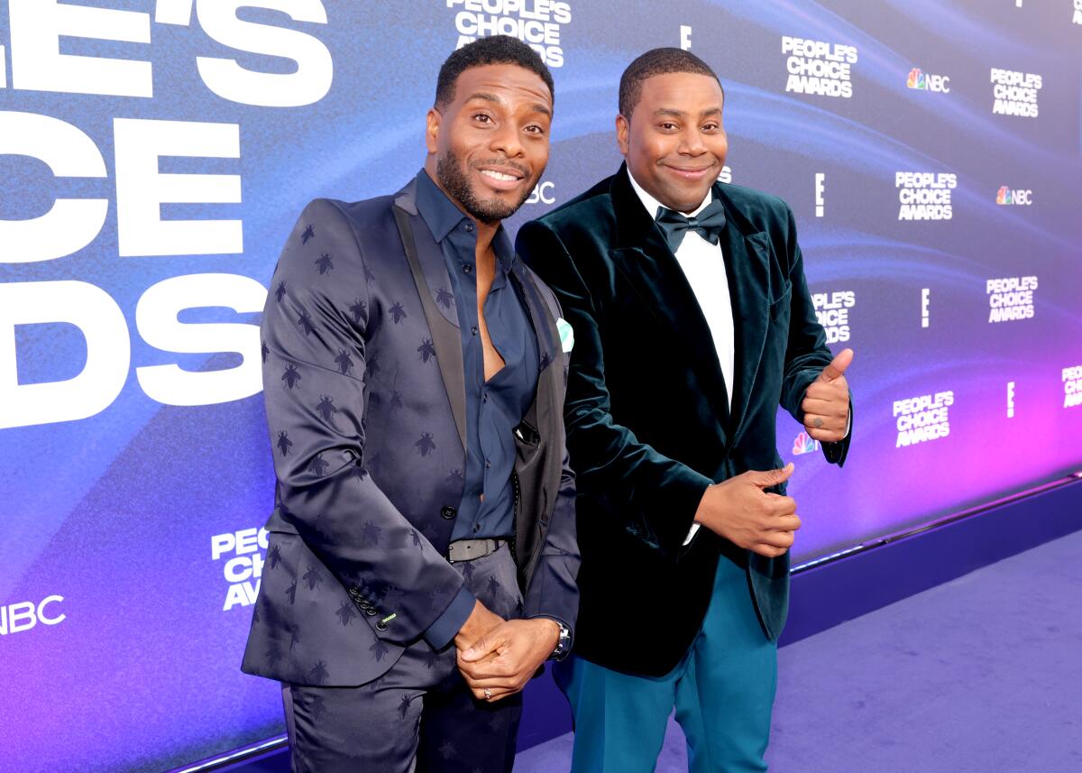 Kel Mitchell and Kenan Thompson wear suits and smile on a purple carpet at an awards show