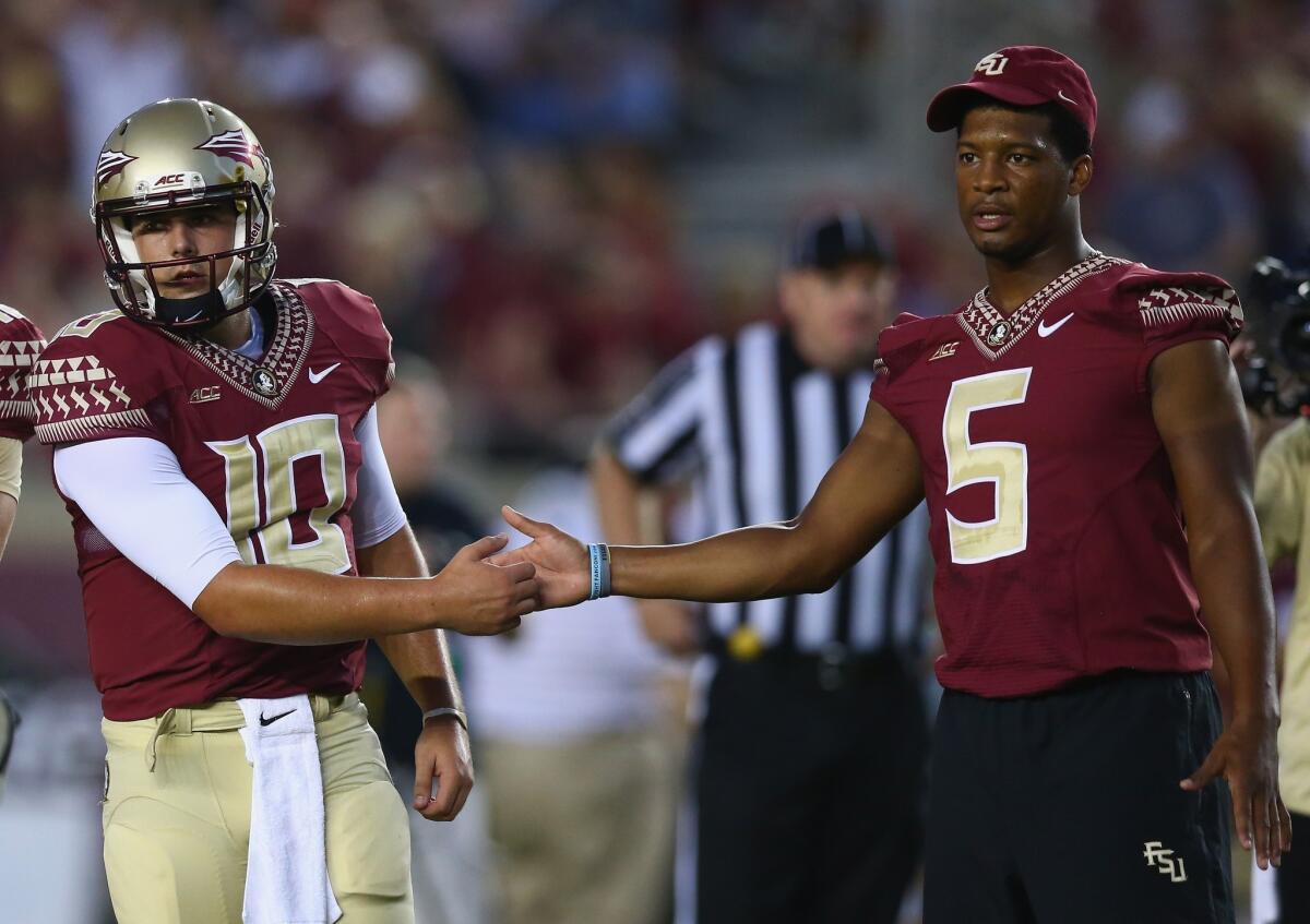 Suspended Florida State quarterback Jameis Winston shakes hands with backup QB Sean Maguire before the Clemson game on Saturday.
