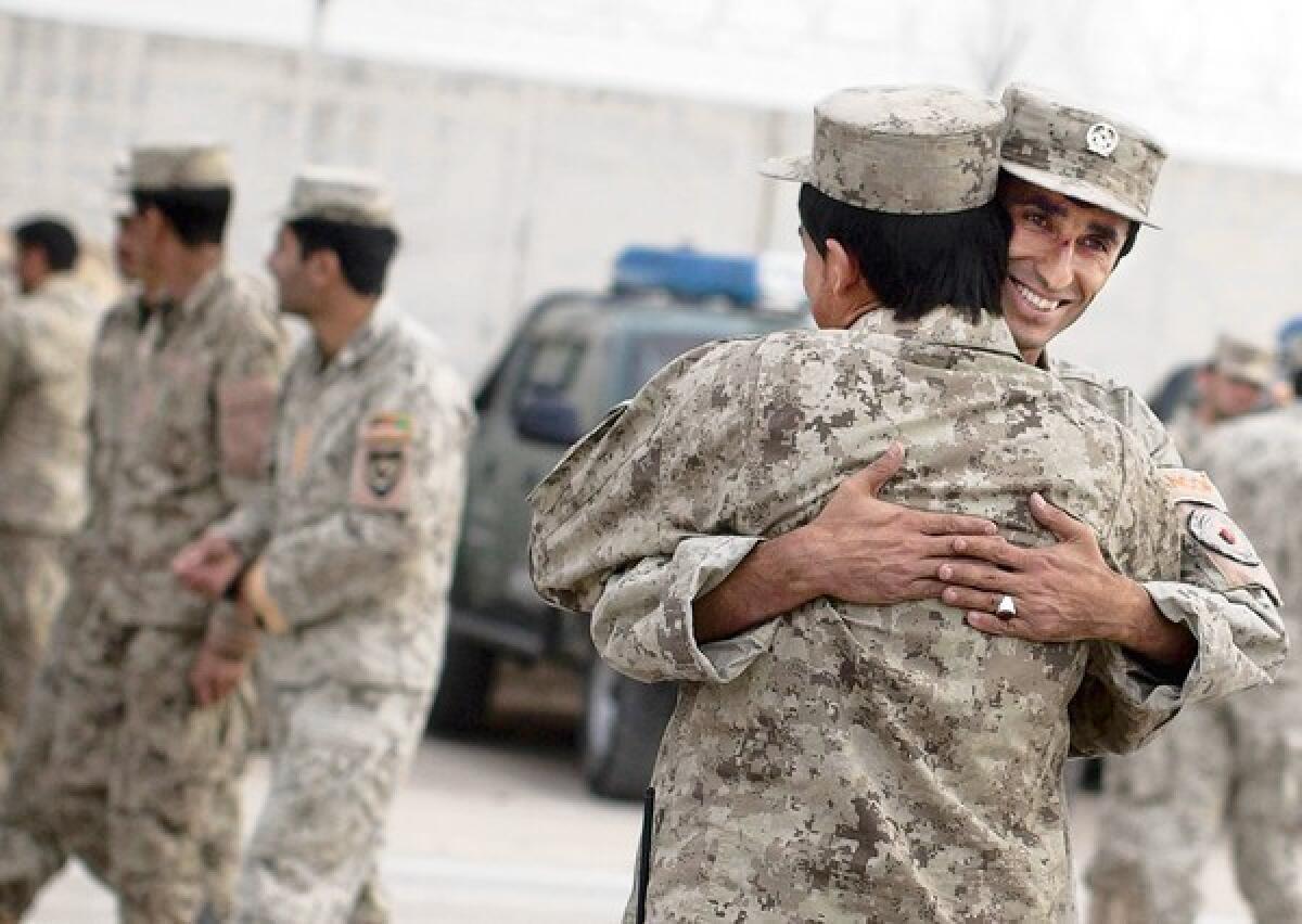 Afghan national policemen embrace each other after a morning drill Oct. 18 at their base in Lashkar Gah, in Afghanistan'sHelmand Province.
